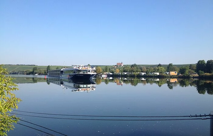 Kreuzfahrtschiff auf dem Main. Im Hintergrund Wohnmobile am Ufer