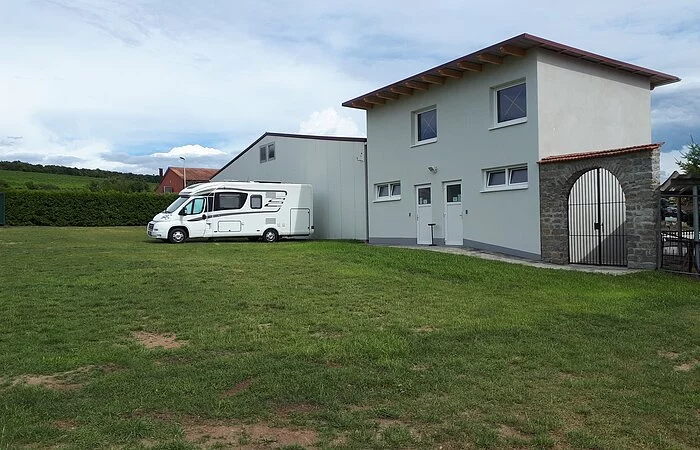 Ein Wohnmobil auf der Wiese vor einem Gebäude