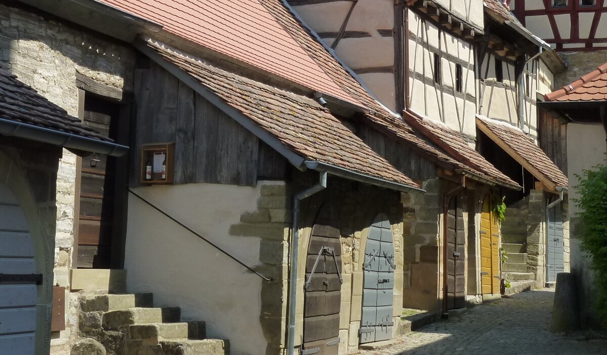 Häuserreihe, z.Tl. mit Fachwerk, niedrige Dächer und Steintreppe links