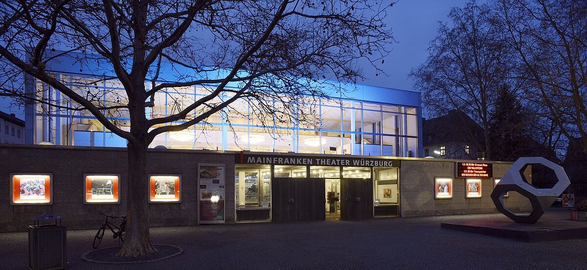 Beleuchtetes Theatergebäude von außen bei Nacht