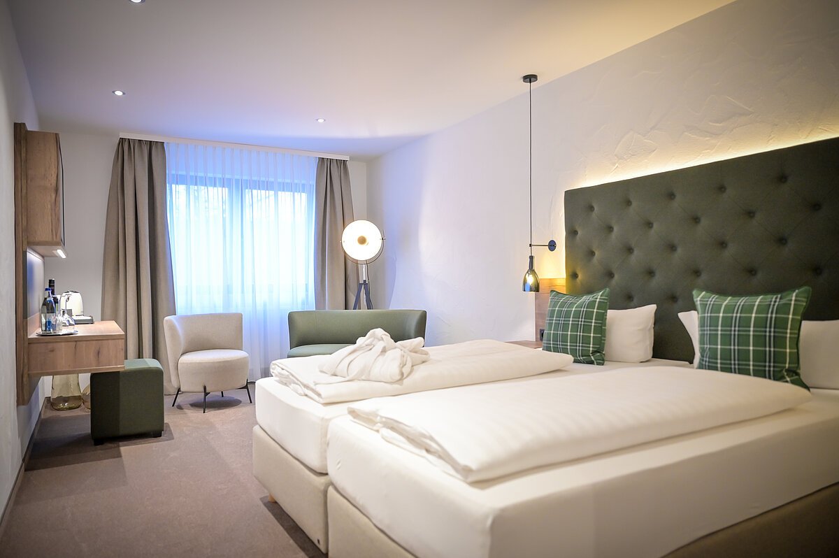 Boxspringbett mit Zimmeransicht in den Farben grün, weiß und beige