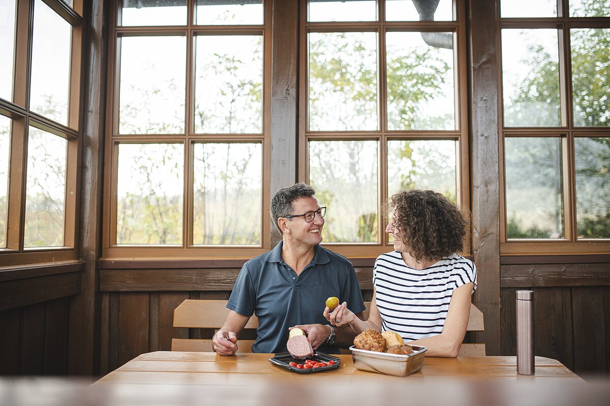Zwei Menschen machen Brotzeit in einer Hütte