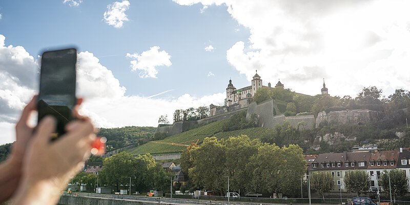 Blick auf die Festung Marienberg in Würzburg. Frau macht mit Smartphone ein Foto.