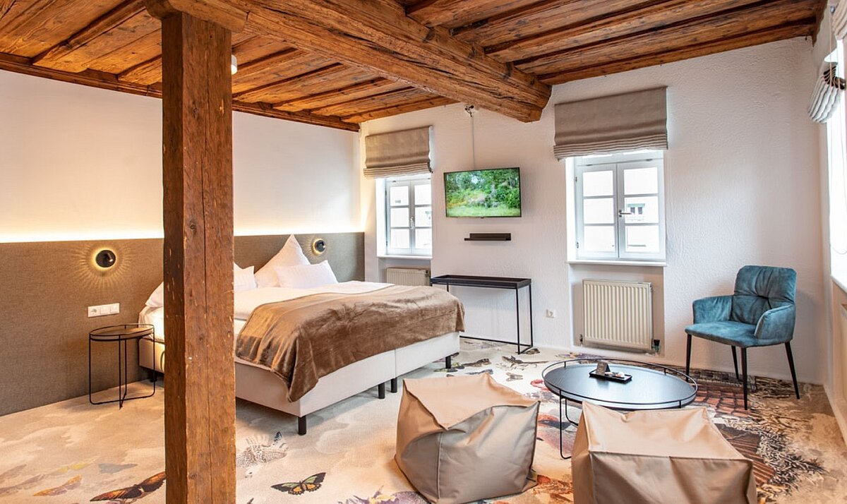 Zimmer in weißen, beigen und braunen Tönen mit Doppelbett und Holzbalkendecke