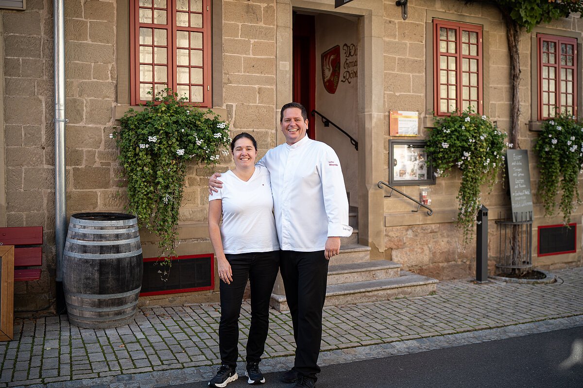 Das Inhaberpaar stehen vor ihrem Gasthaus und Hotel Winzerstube in Rödelsee.