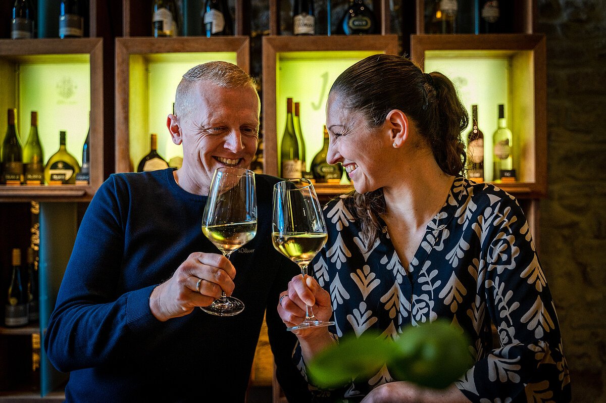 feinschmeckermesse iphofen zwei menschen stoßen lachend zusammen mit wein an