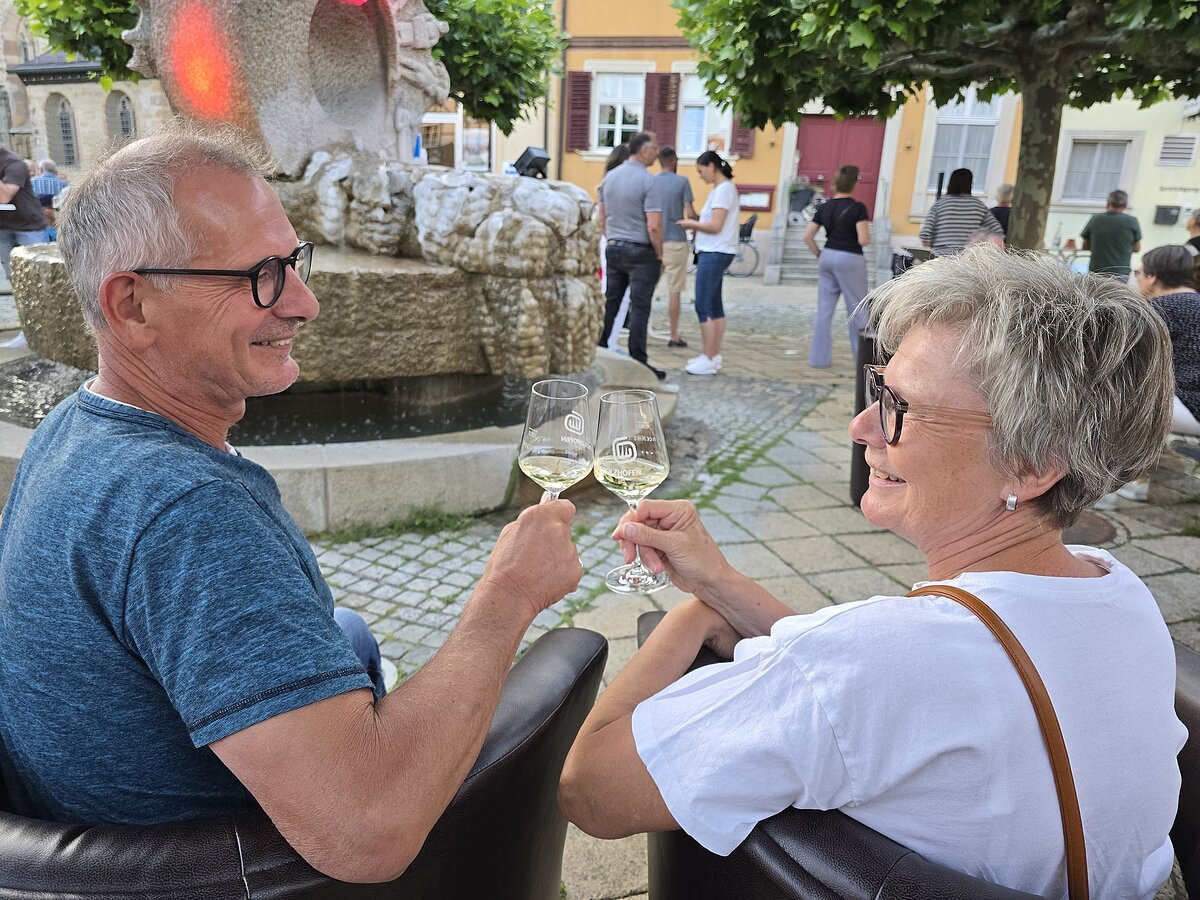 Brunnenshoppen Marktplatz freudige menschen stoßen mit glas wein an