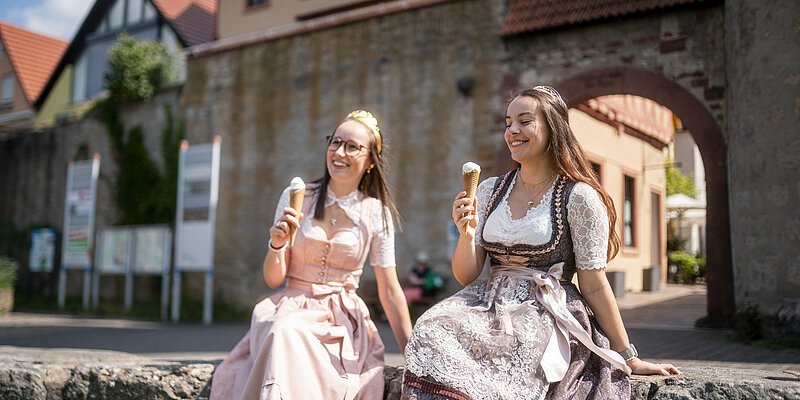 header weinprinzessinen sitzen auf einer mauer und essen eis