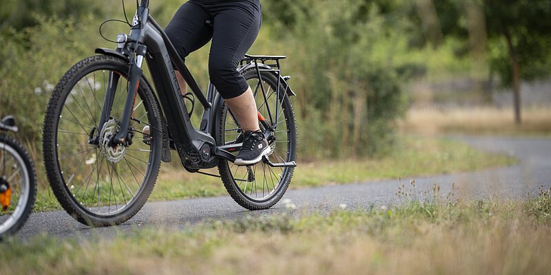 Eine Frau fährt mit dem E-Bike auf einem Radweg.